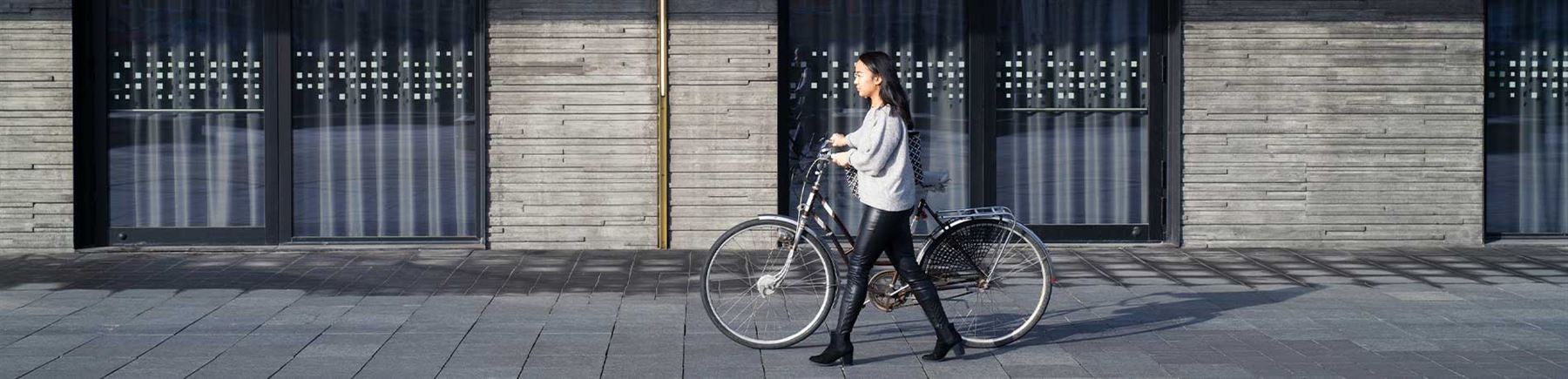 En kvinna leder sin cykel genom staden