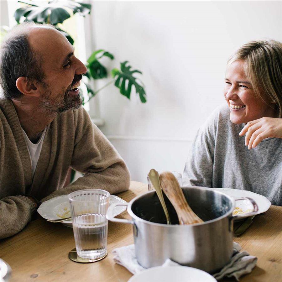 Två äldre personer pratar om pension vid matbordet.