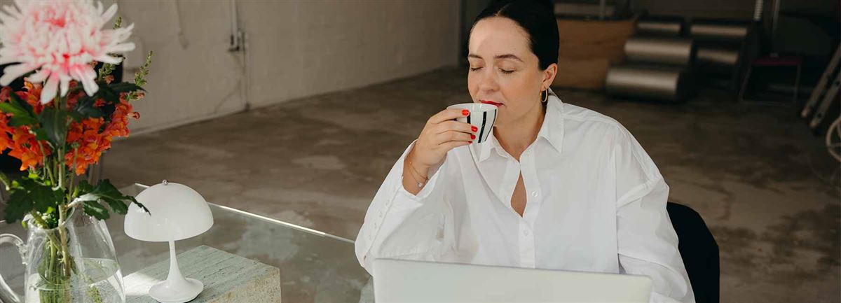 En kvinna sitter i en fotölj och dricker kaffe.