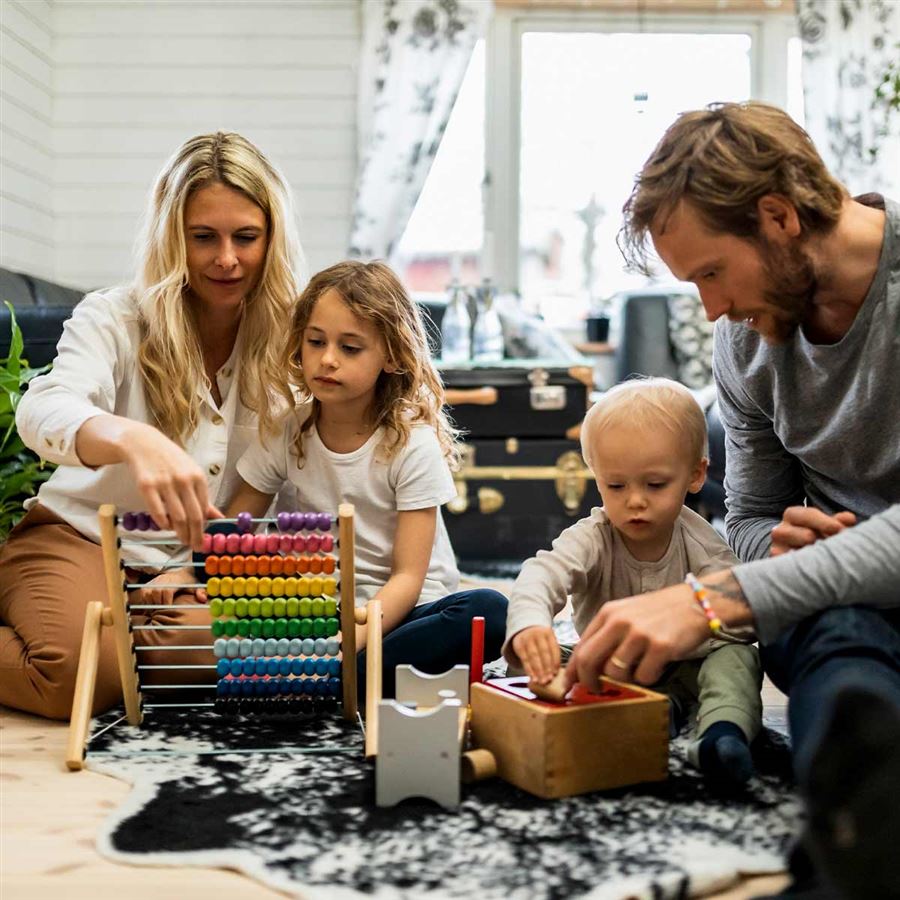 Familj tillsammans på golvet räknar på en kulram.